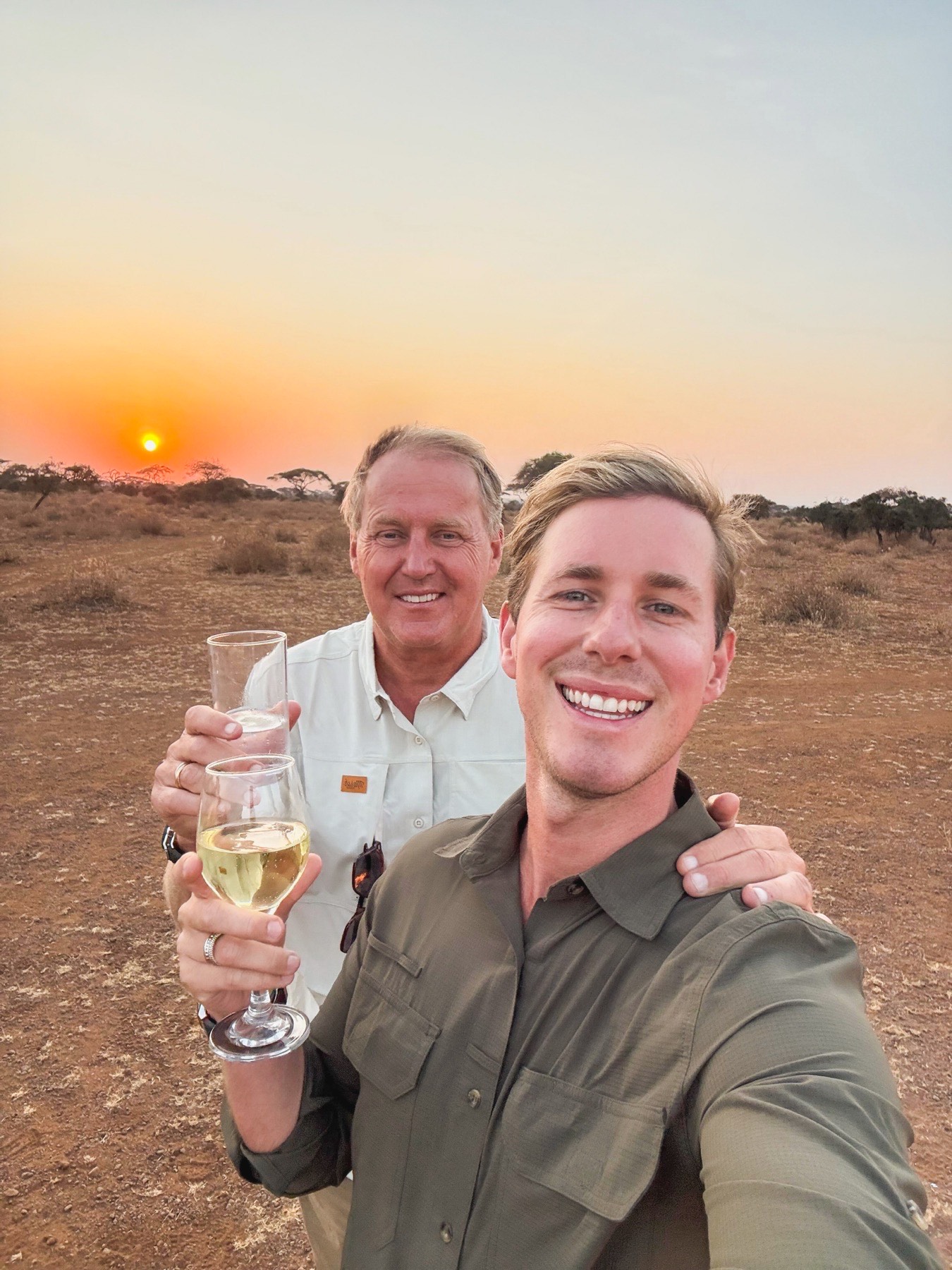 Thibault and Billy raising a sunset toast together on safari